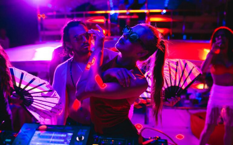 Three people dancing abord a full moon party transfer crusie