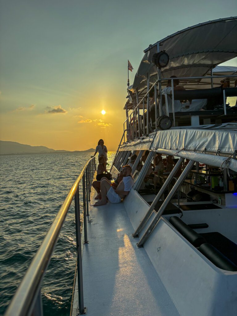 Two people wathing a sunset from the site of a power catamaran