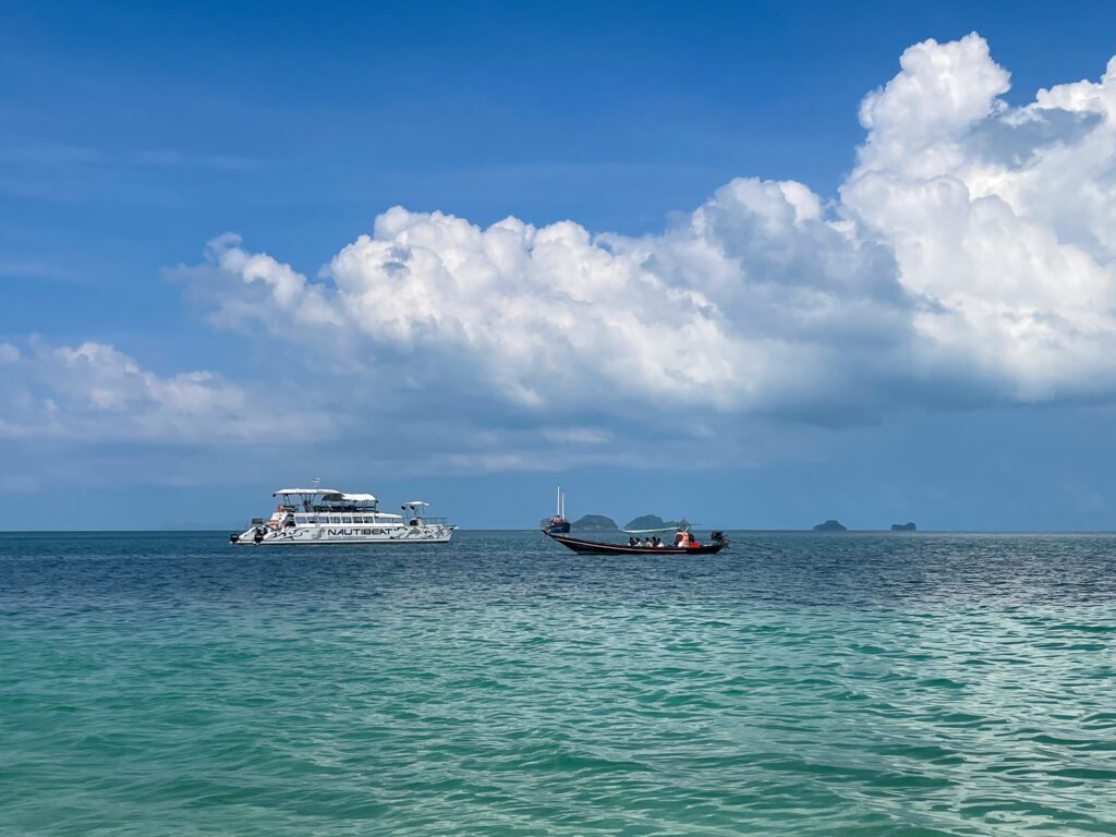 A luxury catamaran floating next ot a long tail boat