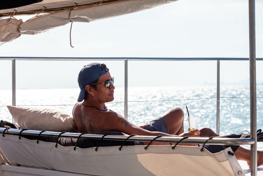 A man on a boat leaning back in his seat with a drink in his hand